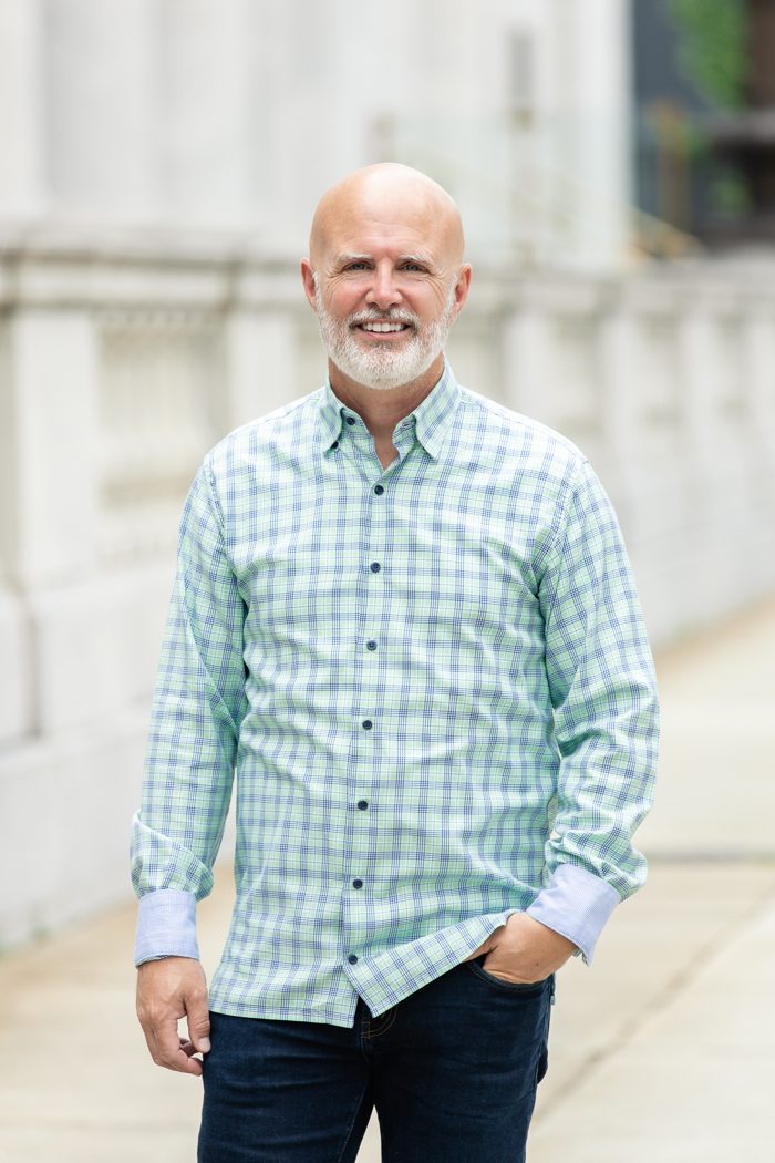 Mark Machen, President of Harmony IT, standing outdoors in a plaid button-down shirt